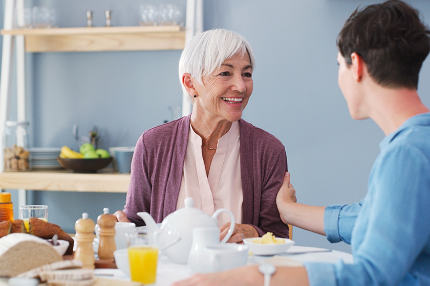 I am so glad I can have breakfast with you. a happy senior woman sitting and having breakfast with her attractive young daughter while at home — Photo